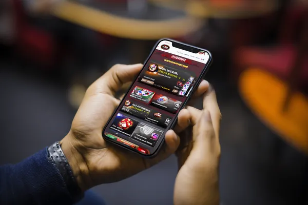 A man focused on his laptop with live stats in the background, highlighting the dedicated sports and gaming features of the KK333 mobile app.